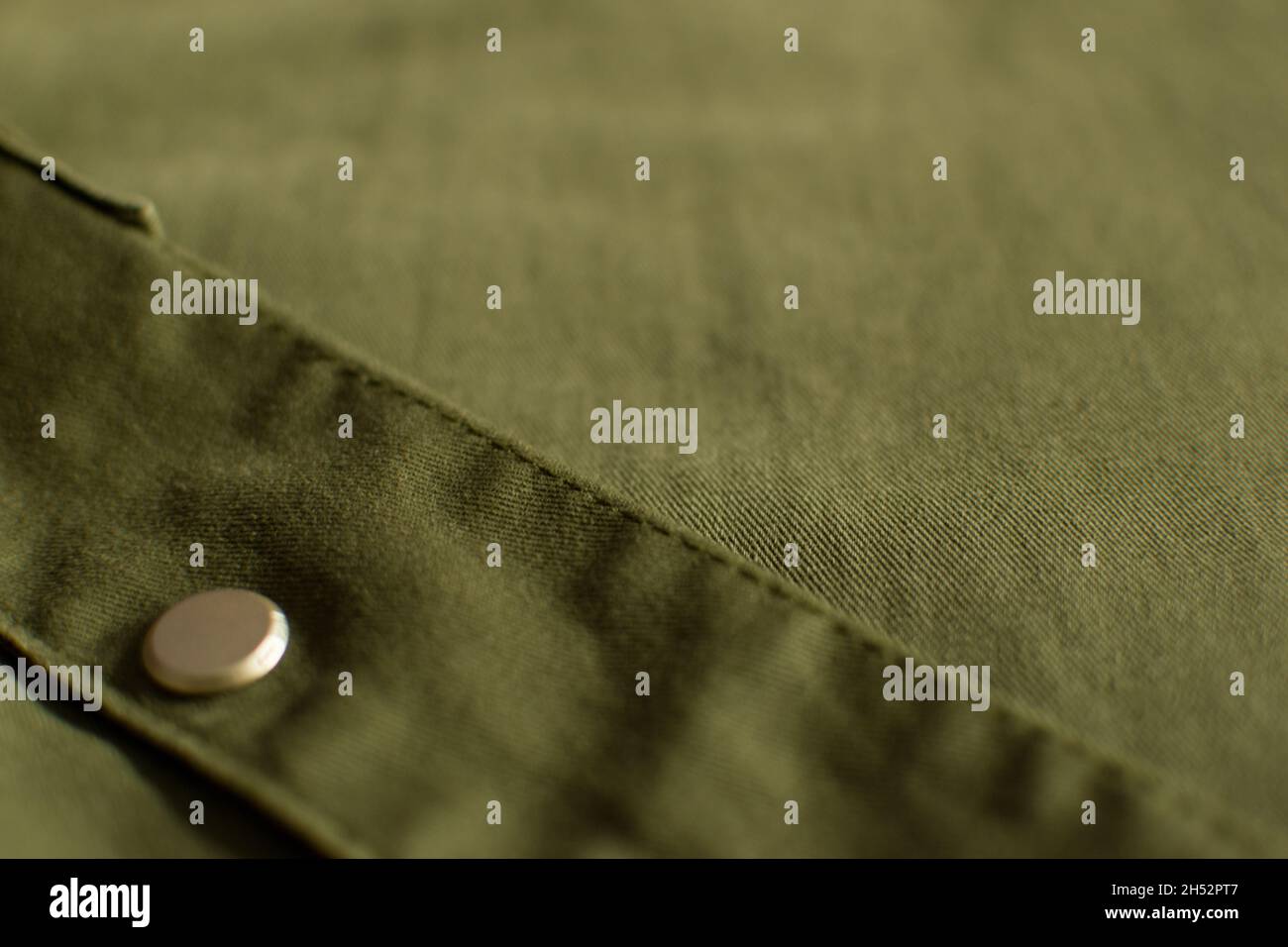Close up of olive green military uniform fabric with metal button Stock Photo