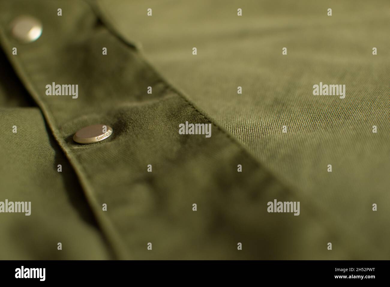 Olive green military uniform with metal button background, close up, copy space Stock Photo