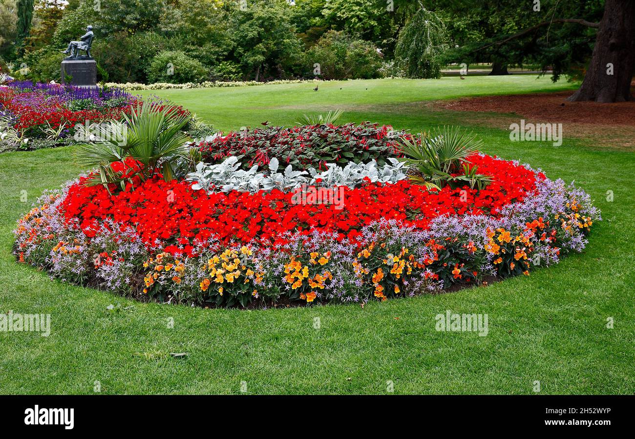 colorful flower bed, circle, multiple colors, green grass, trees