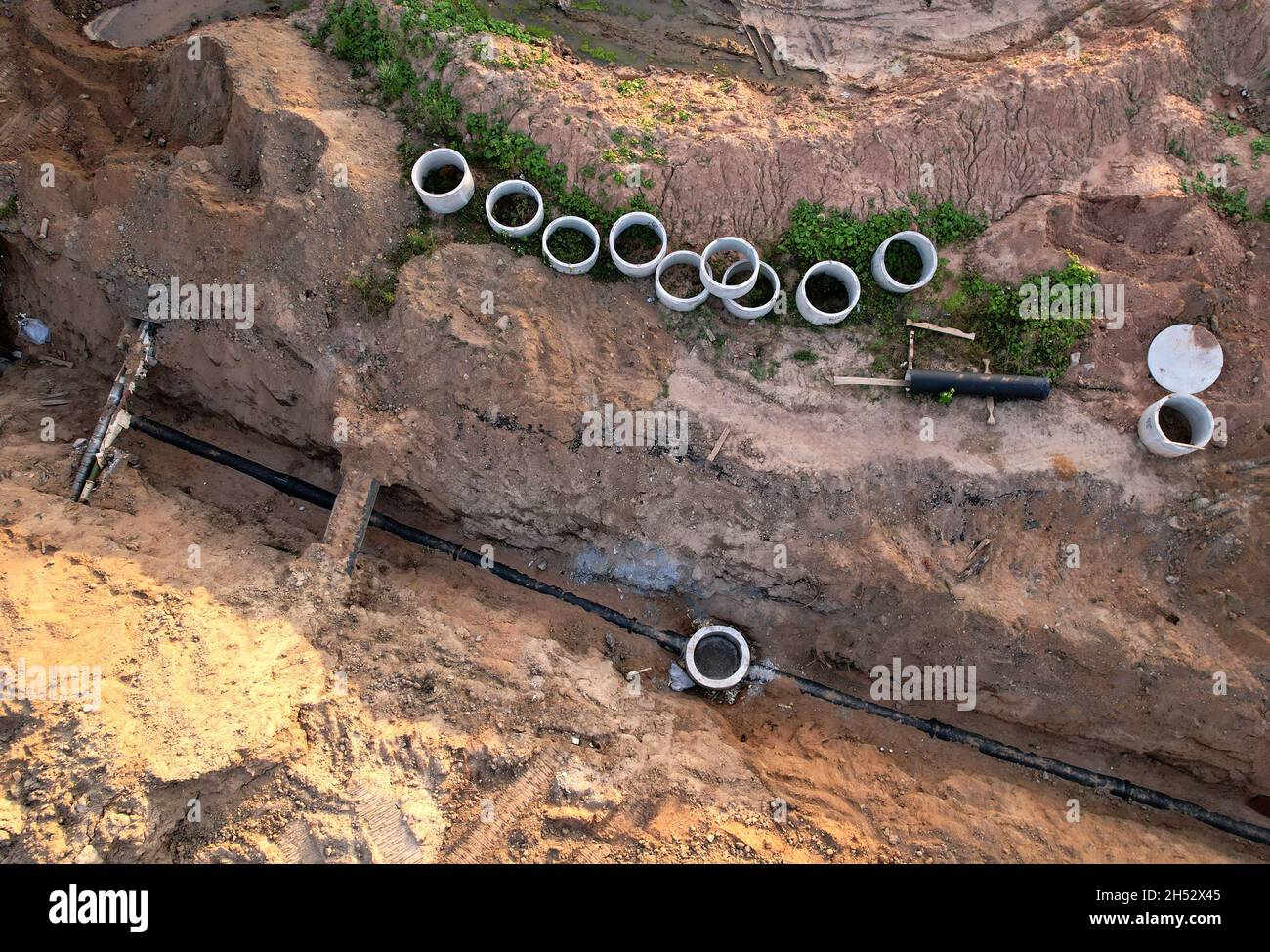 Laying of underground storm sewer pipes and sewerage well. Construction of water main, sanitary sewer, storm drain systems. An aerial view of the conc Stock Photo