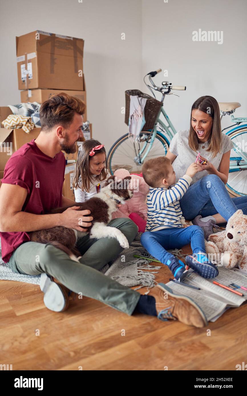 Happy mother and father with a kids moving in new home and having fun ...