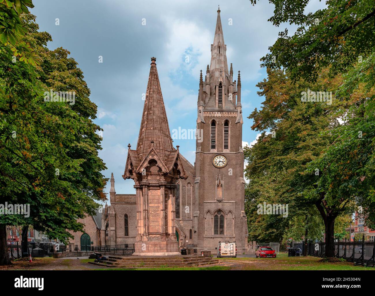 St John's Anglican Church in Stratford Broadway, with the Stratford Martyrs Memorial in the churchyard. Grade II listed buildings. Stratford, London, Stock Photo