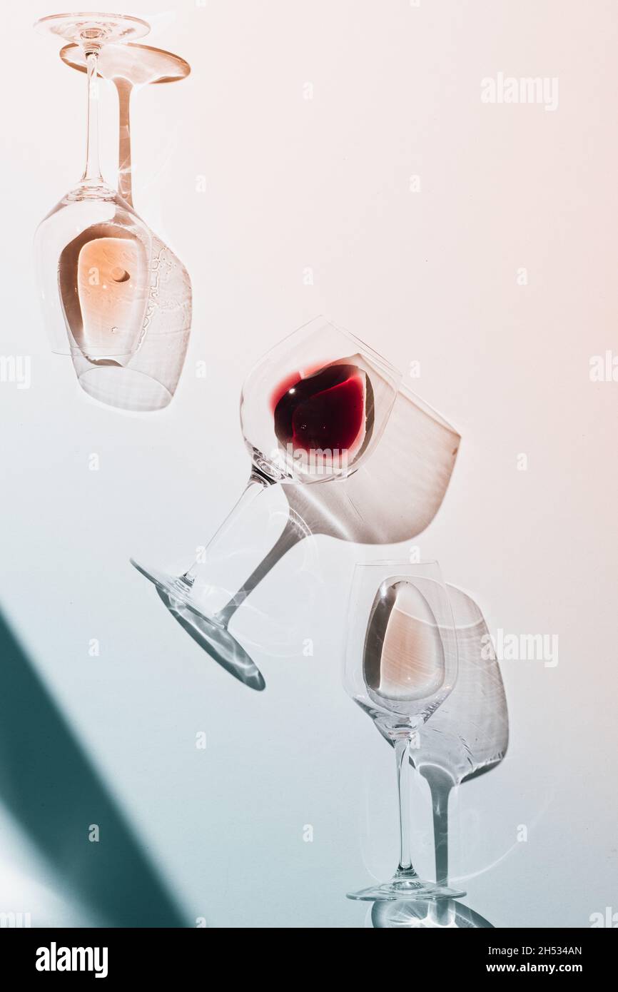 Glasses of red and rose wine on a white table. Strong emotional light with hard shadows. Moody and colorful  refractions. Stock Photo