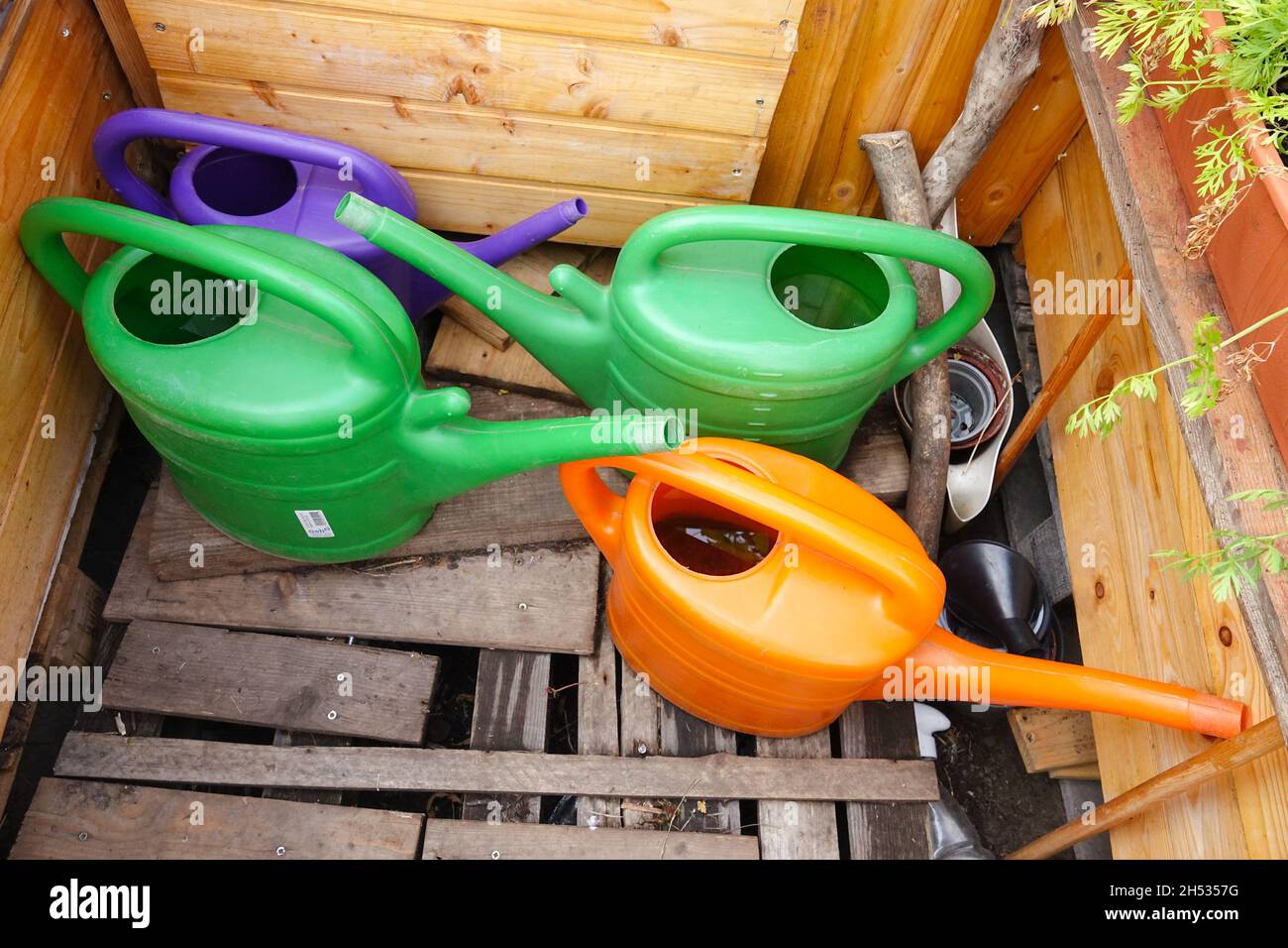 Colourful plastic watering cans in garden Stock Photo Alamy