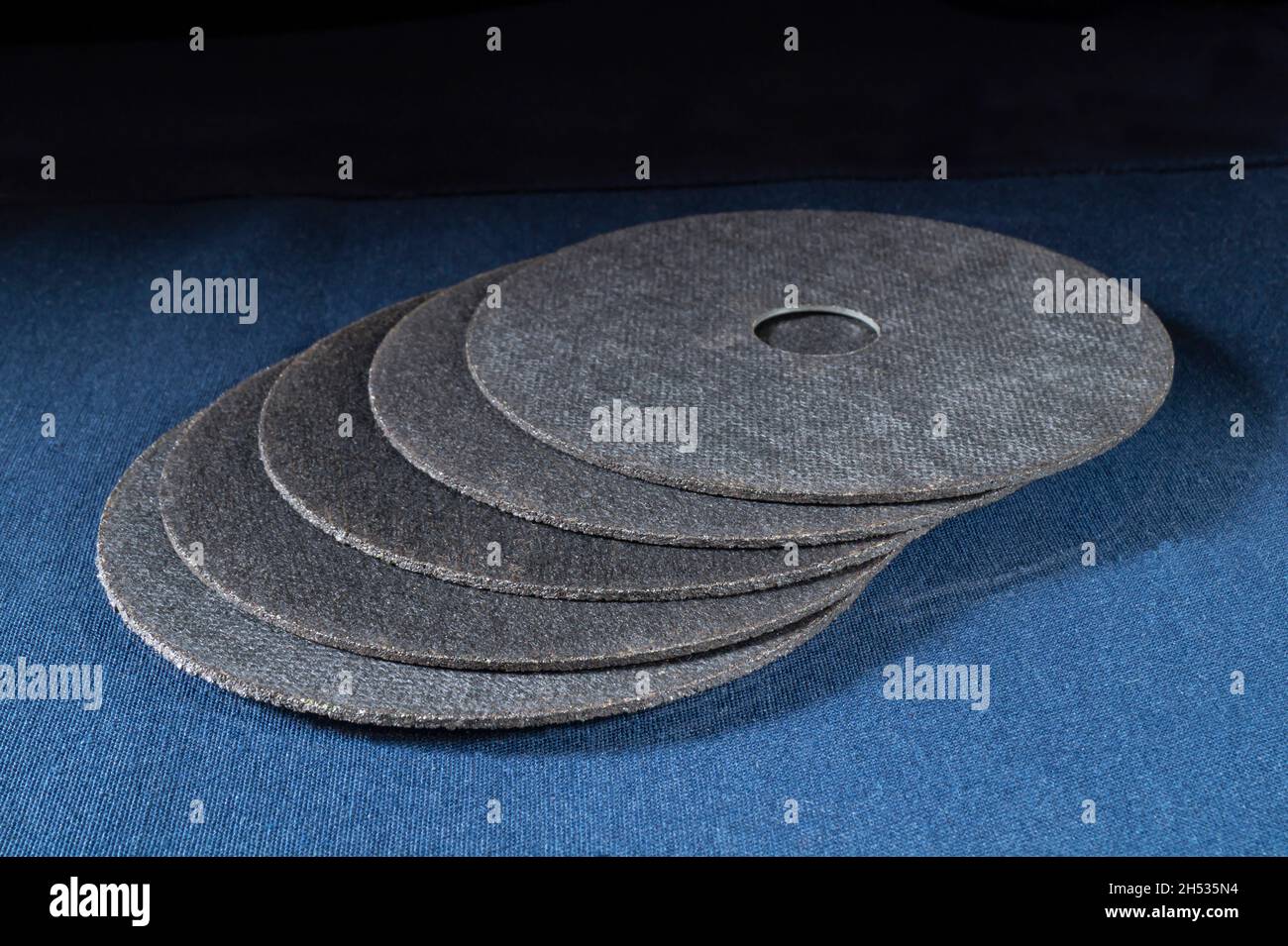 A cutting disc for a grinder on a blue table. Locksmith tools on a black background Stock Photo