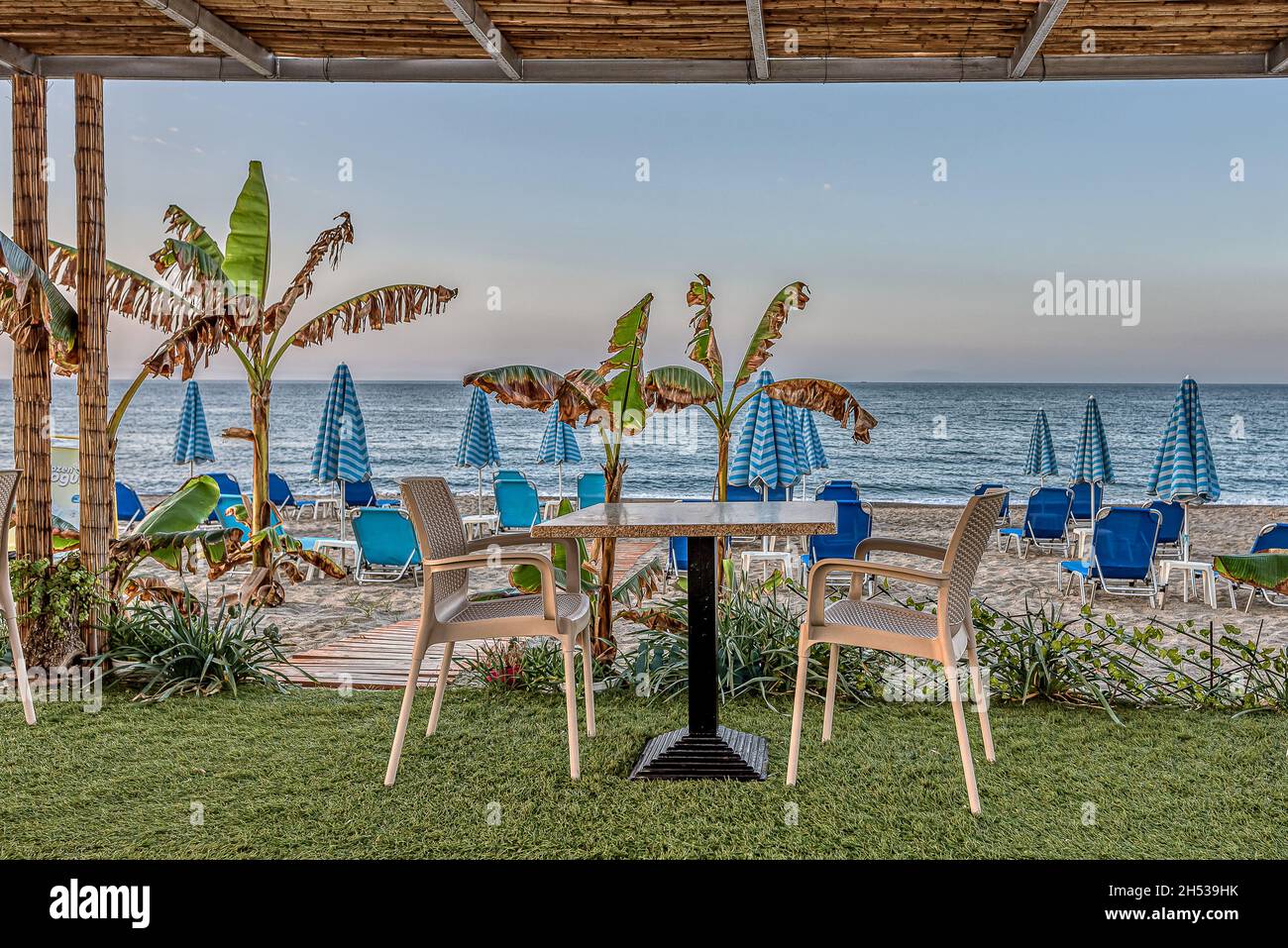 a table for two in a greek tavern overlocking the beach and the azure Mediterranean Sea, Crete, Greece, October 11, 2021 Stock Photo