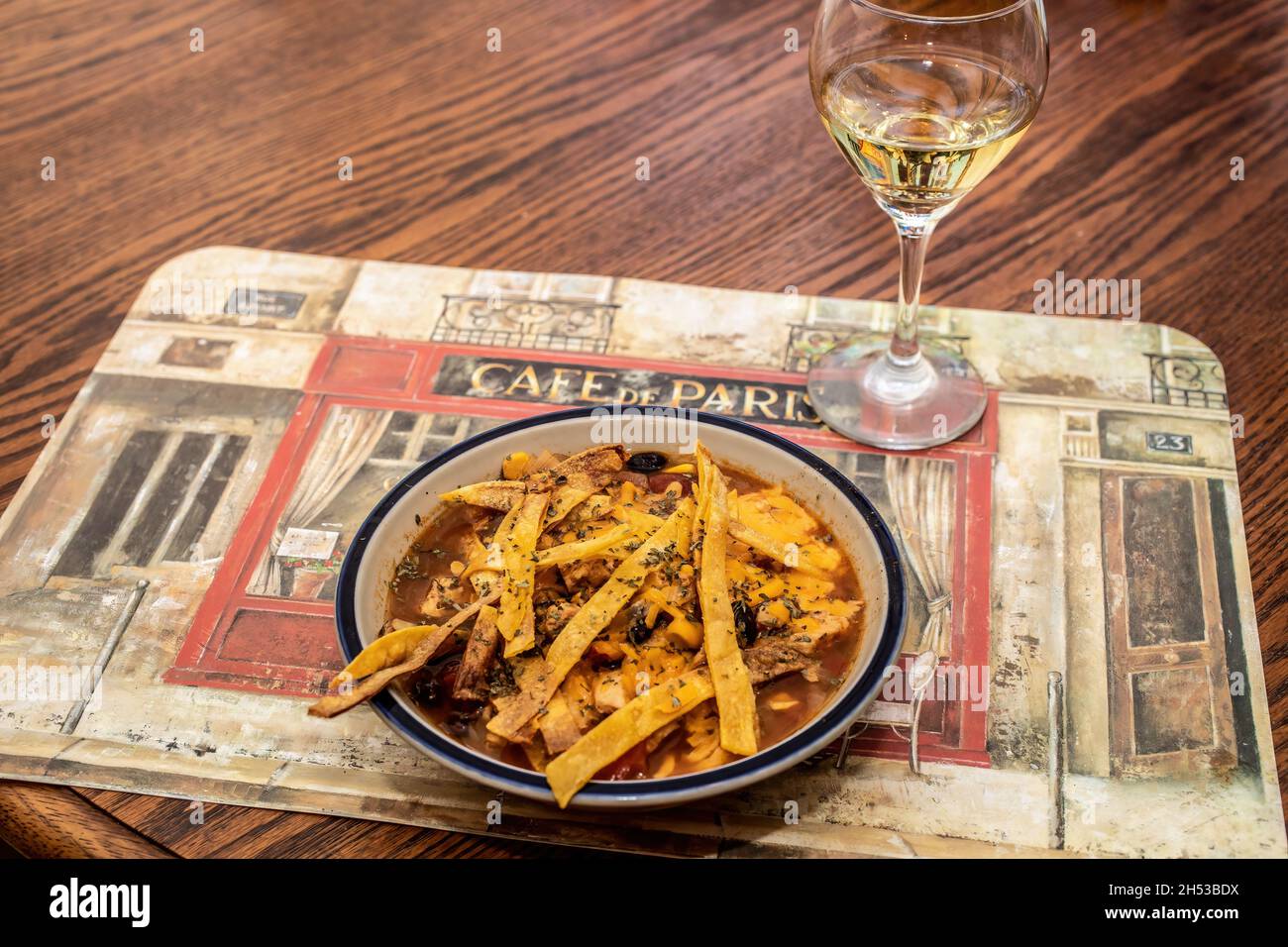Chicken tortilla soup with white wine, 'Jig' on a Cafe de Paris placemat. Stock Photo