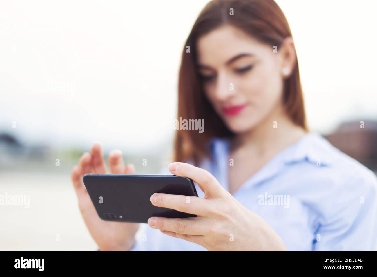 Young redhead Caucasian businesswoman messaging outdoors depth of field Stock Photo