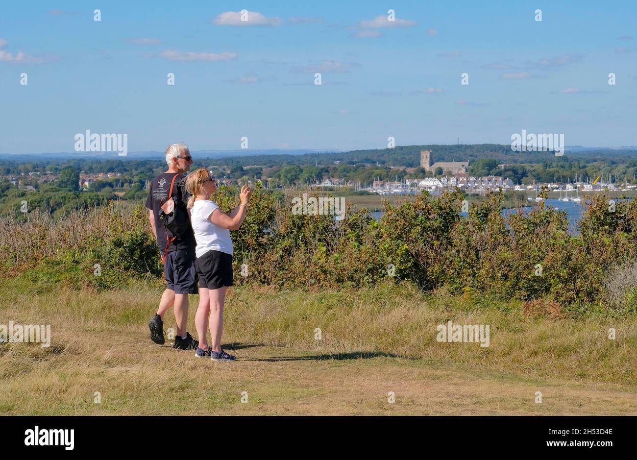 Young Couple standing on Hengistbury Head taking a photograph with a smart phone overlooking Christchurch Harbour, Dorset, England, UK Stock Photo