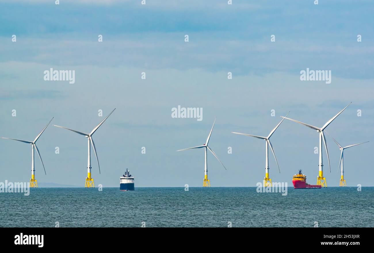 Offshore supply ships anchored by wind turbines in offshore wind farm seen from Aberdeen Bay, North Sea, Scotland, UK Stock Photo