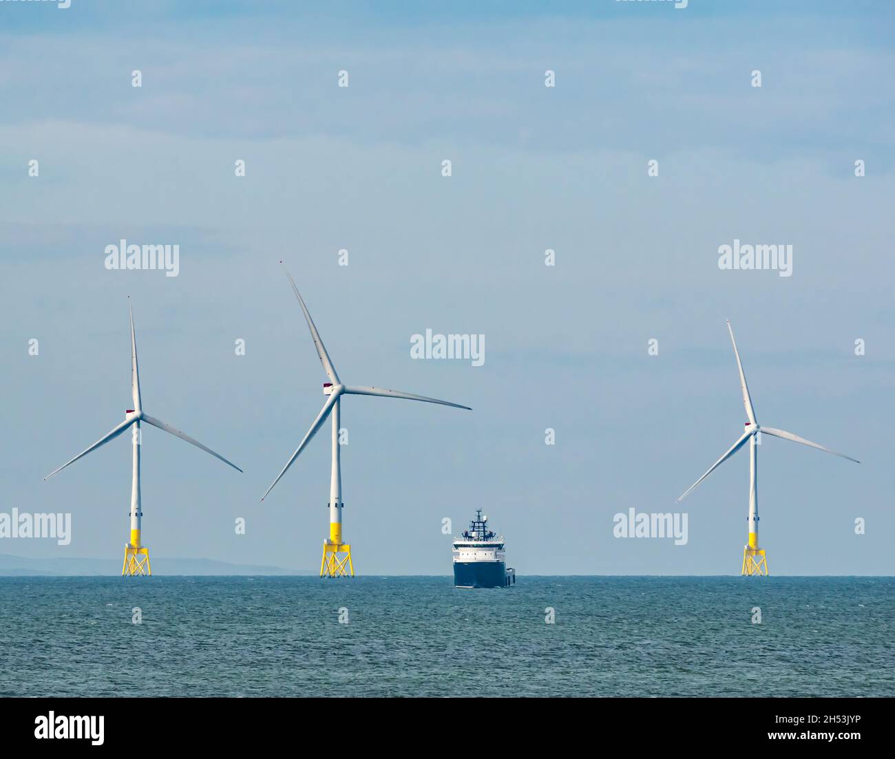 Offshore supply ships anchored by wind turbines in offshore wind farm seen from Aberdeen Bay, North Sea, Scotland, UK Stock Photo