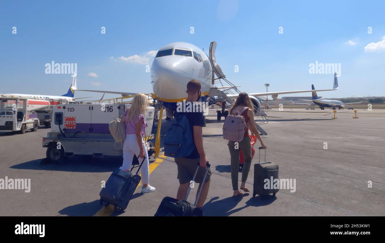 Gudja, Malta airport tarmac passengers outside a Ryanair aircraft. Travelers with masks carrying luggage at apron area of country international MLA airport, boarding a Boing 737. Stock Photo