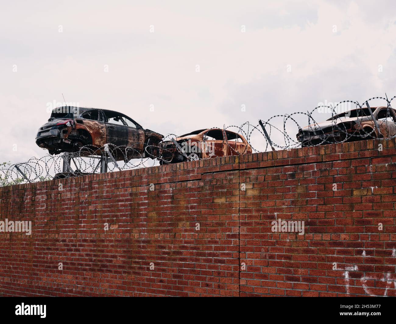 A metal scrapyard with damaged car bodies behind a wall with barbed wire - metal car breakers yard - car recycling Stock Photo