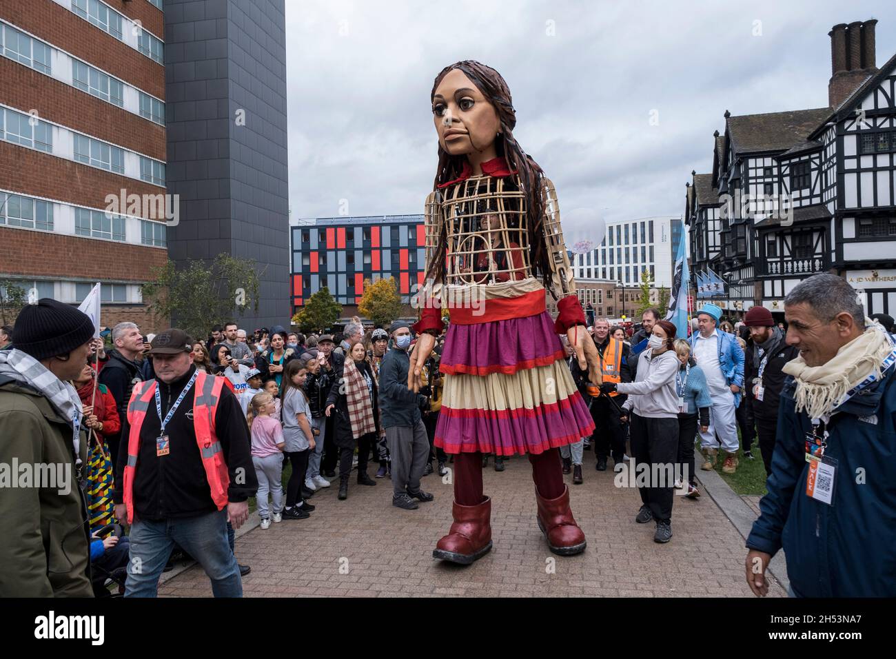 Little Amal delights crowds of onlookers as she walks through the city centre on 27th October 2020 in Coventry, United Kingdom. Little Amal is a 3.5 metre-tall puppet and living artwork of a young Syrian refugee child who has spent the last 3 months walking 8000 km from the boarder of Syria across Turkey, Greece, Italy, France, Switzerland, Germany, Belgium and the UK to focus attention on the urgent needs of young refugees. Coventry, which has the largest Syrian resettlement programme in the region, and also a large population of asylum seekers, is the current city of culture, with a long his Stock Photo