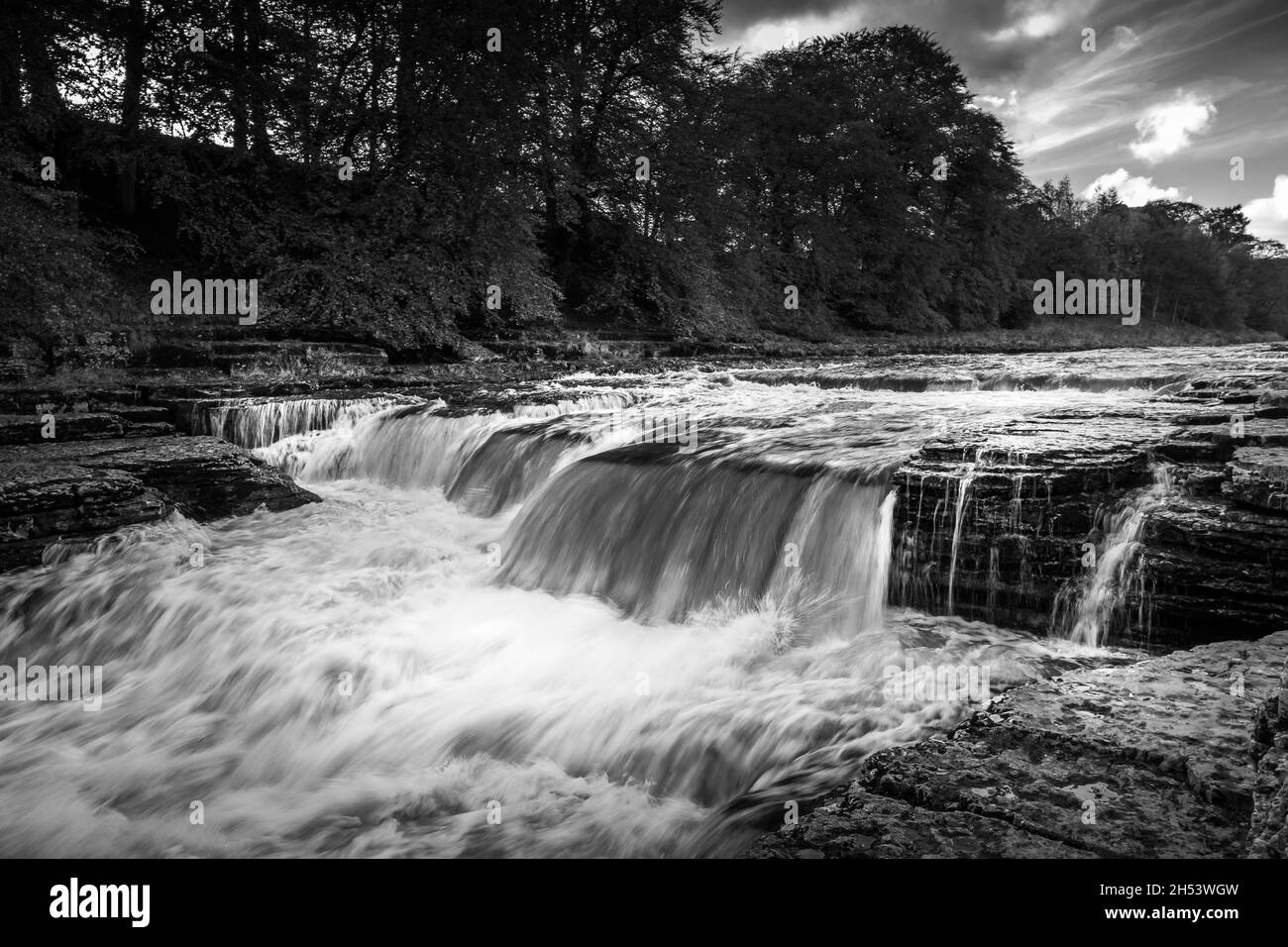 Black and white image of part of the Aysgarth falls in Wensleydale, Yorkshire. Showing river Ure flowing over many of the waterfalls. No people. Stock Photo