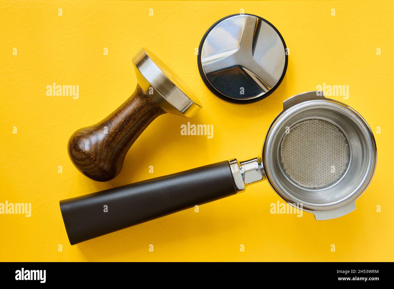 Coffee making tools, coffee basket holder, flattening and tamper on yellow background Stock Photo