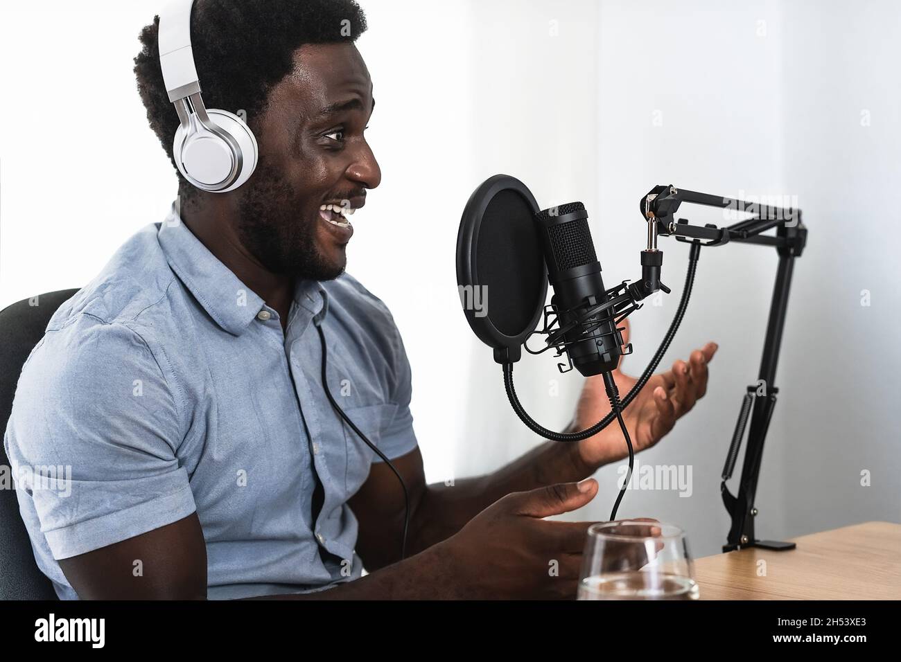 African man recording a podcast using microphone and headphones from his home studio Stock Photo