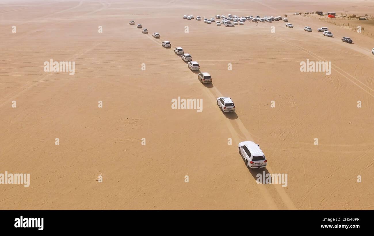 4x4 SUVs cars driving through the sand dunes in the desert of Abu Dhabi. Stock. Top view on SUVs