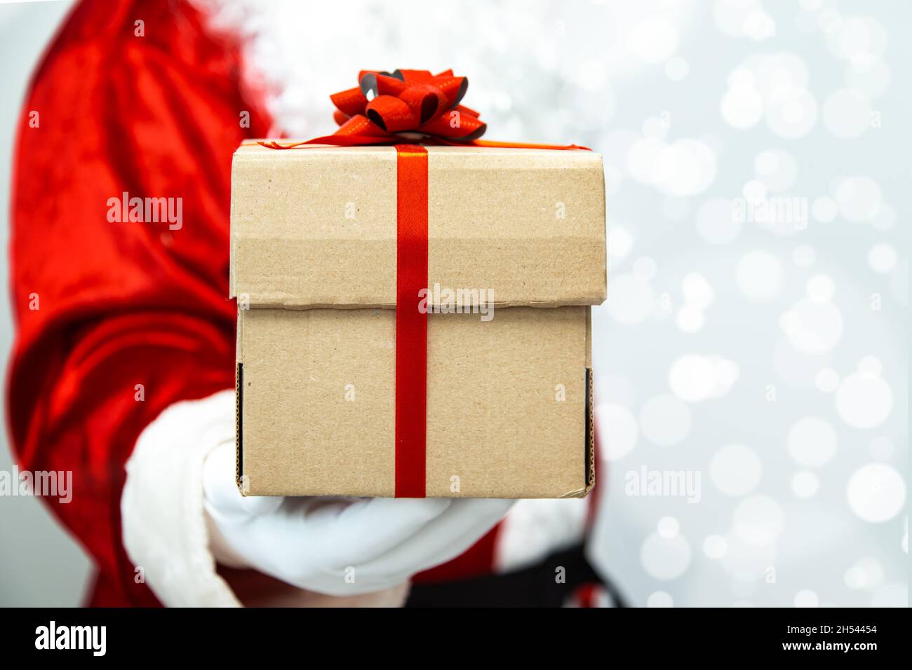 Santa claus gloved hands holding a gift box with red ribbon Stock Photo ...