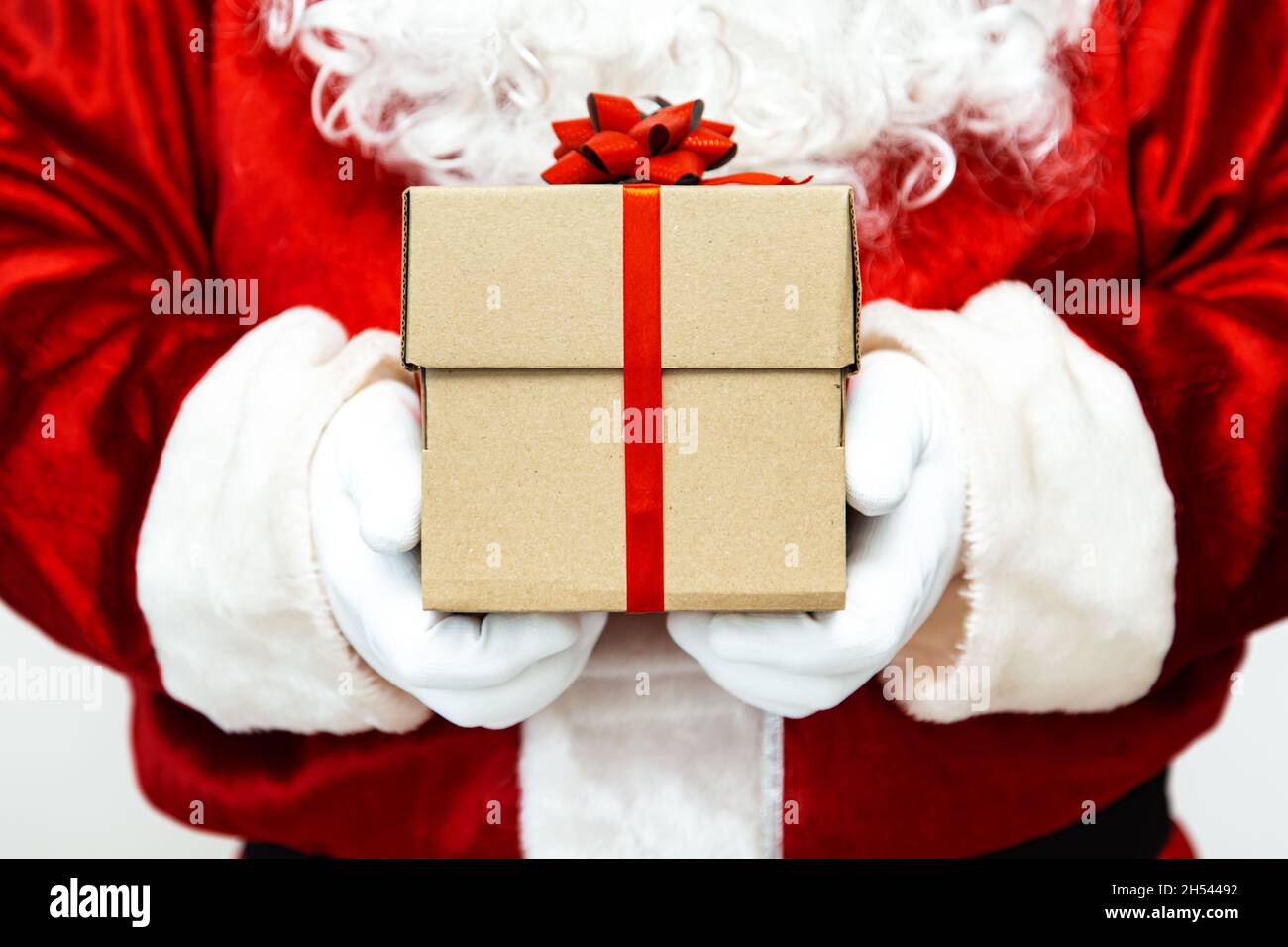 Santa claus gloved hands holding a gift box with red ribbon Stock Photo ...