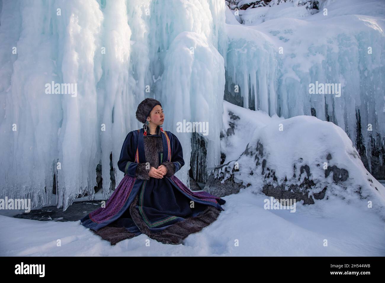 A Buryat girl sitting on the icy cost of a little island on Baikal Lake in winter time Stock Photo