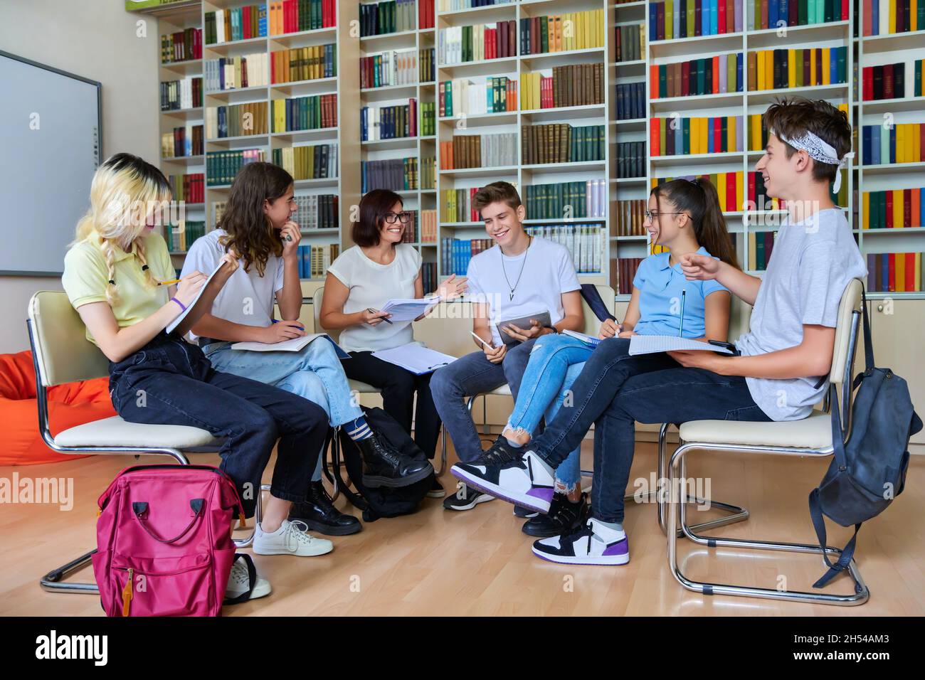 Group of teenagers with middle aged female teacher at library Stock Photo