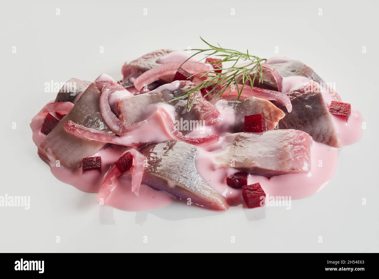 Salad from fresh beetroot and herring fish garnished with dill and served on a white plate Stock Photo