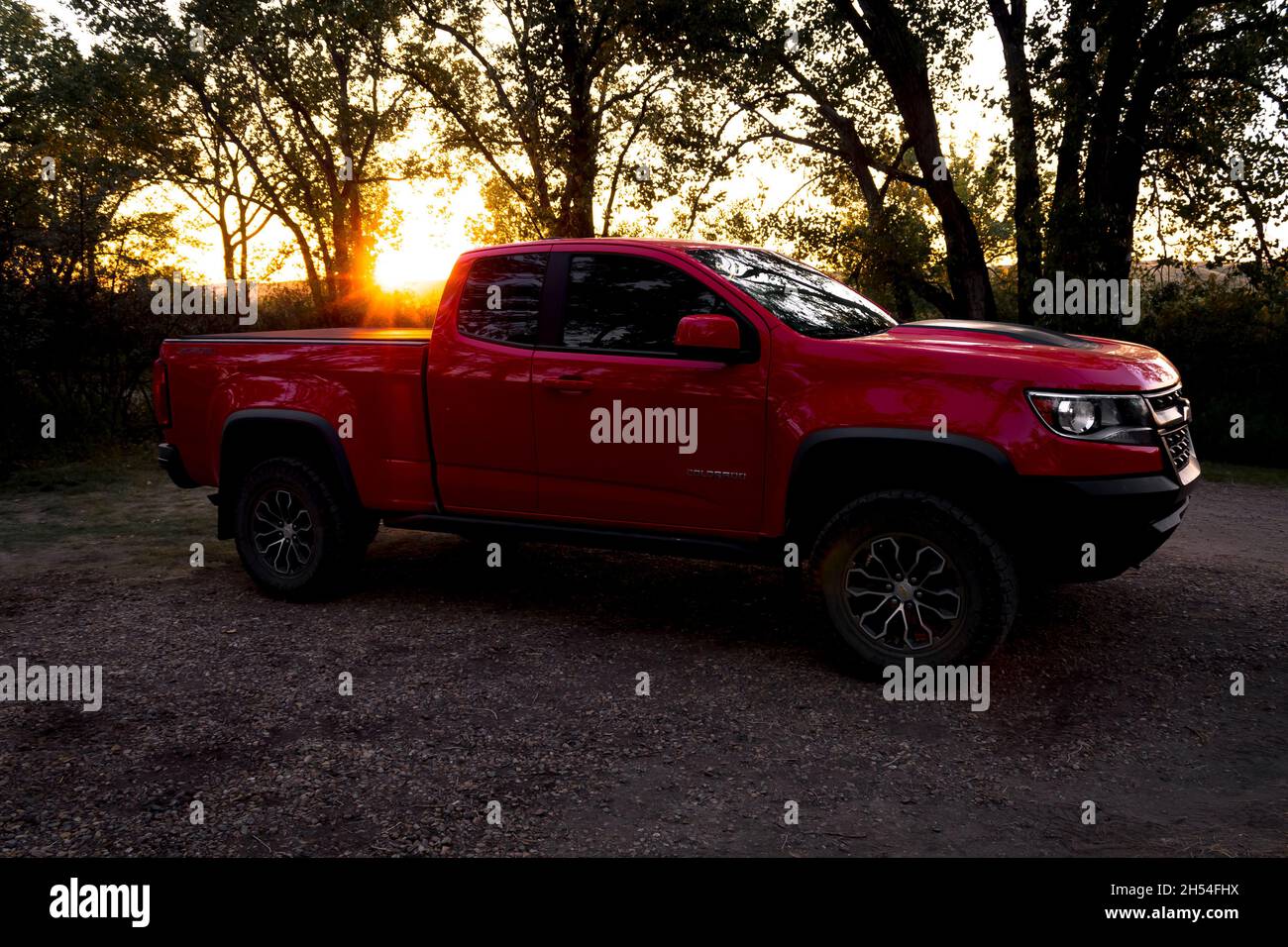 2019 Chevrolet Colorado ZR2 in front of sunset with silhouetted treesparked on gravel with bushes, pale sky poking through Stock Photo