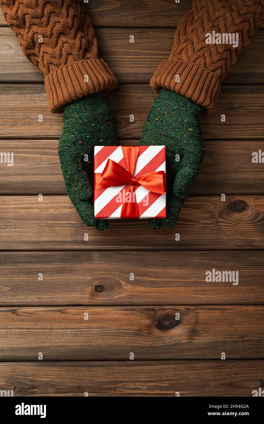 Christmas card with present in the hands of a woman on wooden background with copy space for text Stock Photo