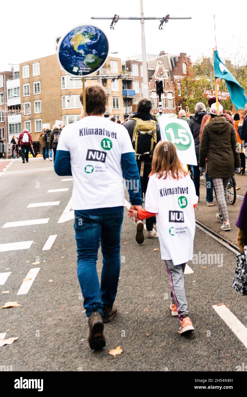 Amsterdam, Netherlands, November 06, 2021. Father and daughter walking hand in hand, seen from the back during the Climat March. They are wearing white T-shirts demanding Climate law NOW, while also requesting to repect the 1,5meter social distance rule.  Credit: Steppeland/Alamy Live News Stock Photo