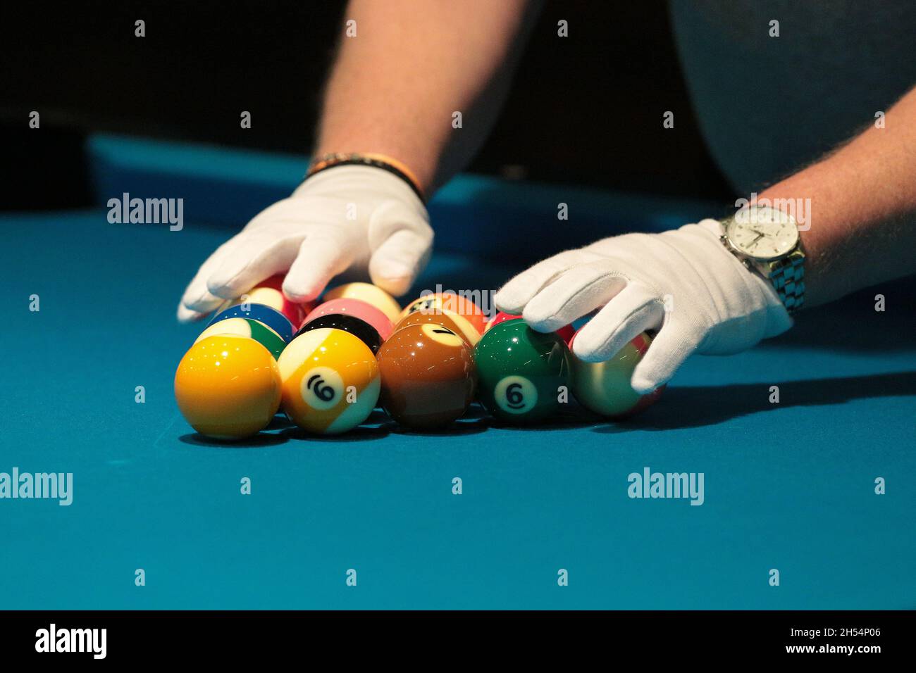 A referee checks, with white gloves, the billiard balls lying in a triangle. Stock Photo