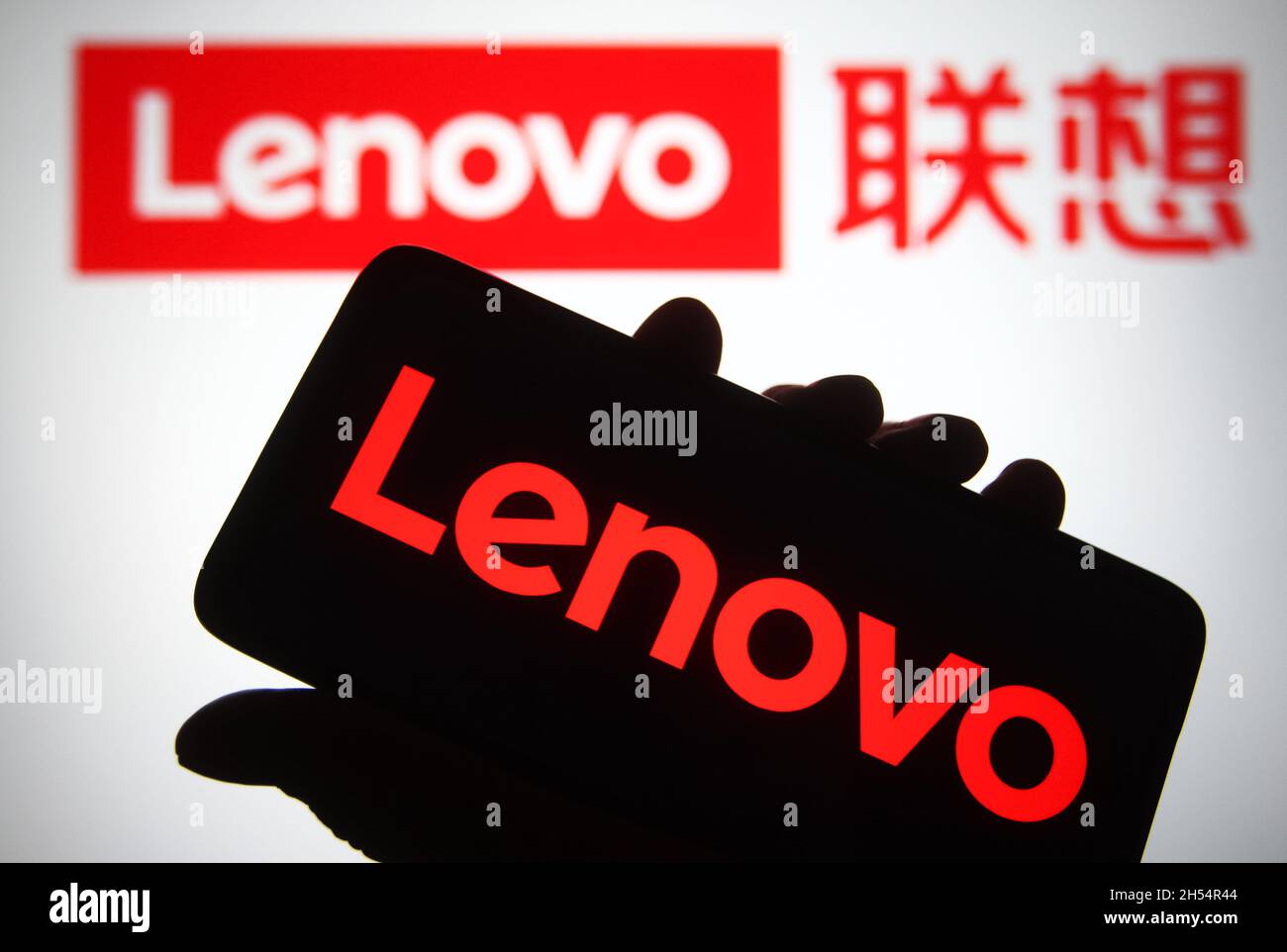 In this photo illustration a Lenovo logo is seen on a smartphone and a pc  screen Stock Photo - Alamy