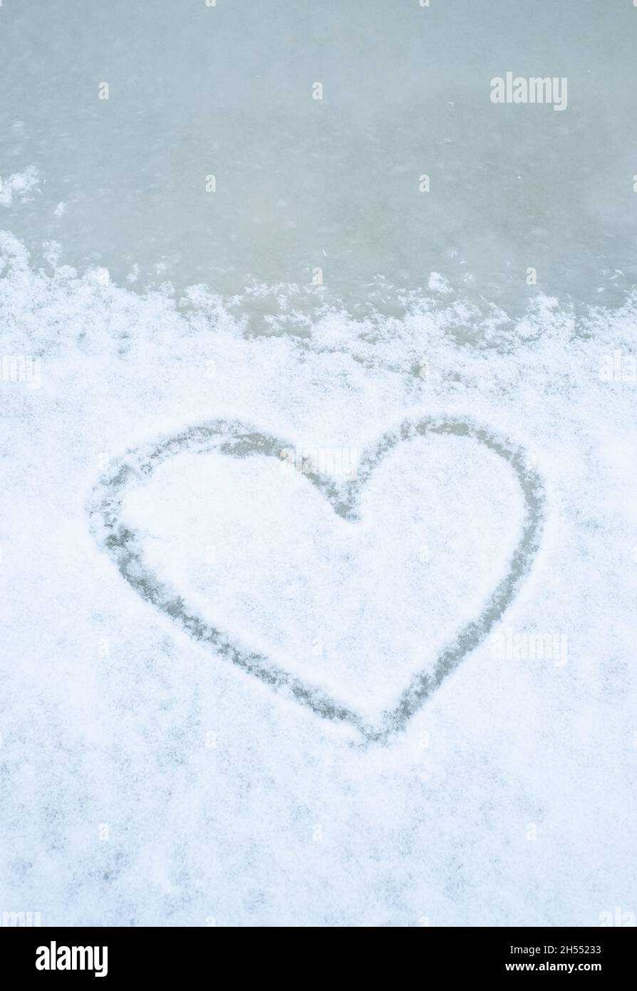Love winter season. Heart shape drawn into snow on ice. Stock Photo