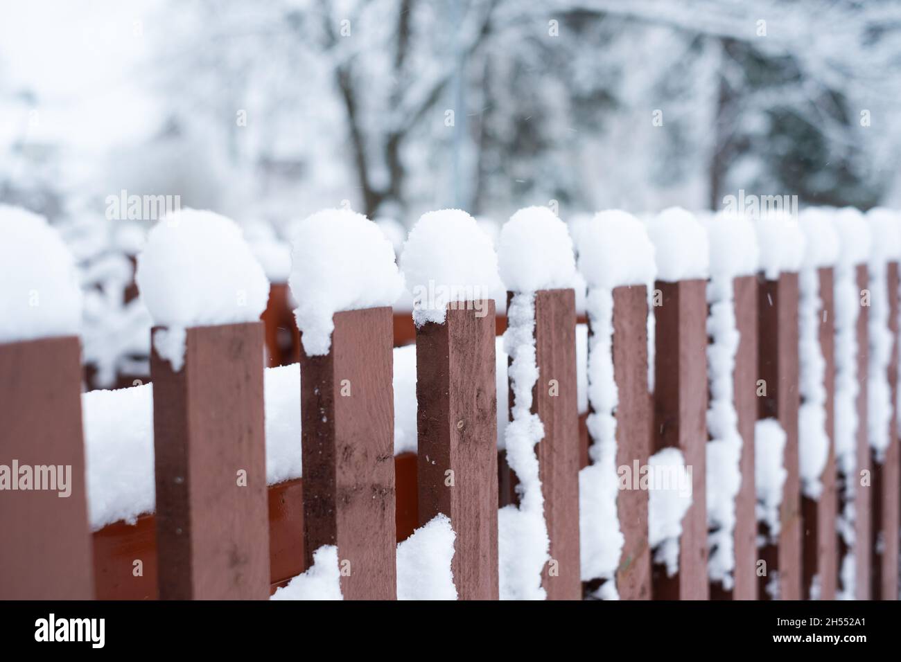 Snow cover. Winter weather. Garden under snow. Close-up of wooden fence covered in snow during winter season. Stock Photo