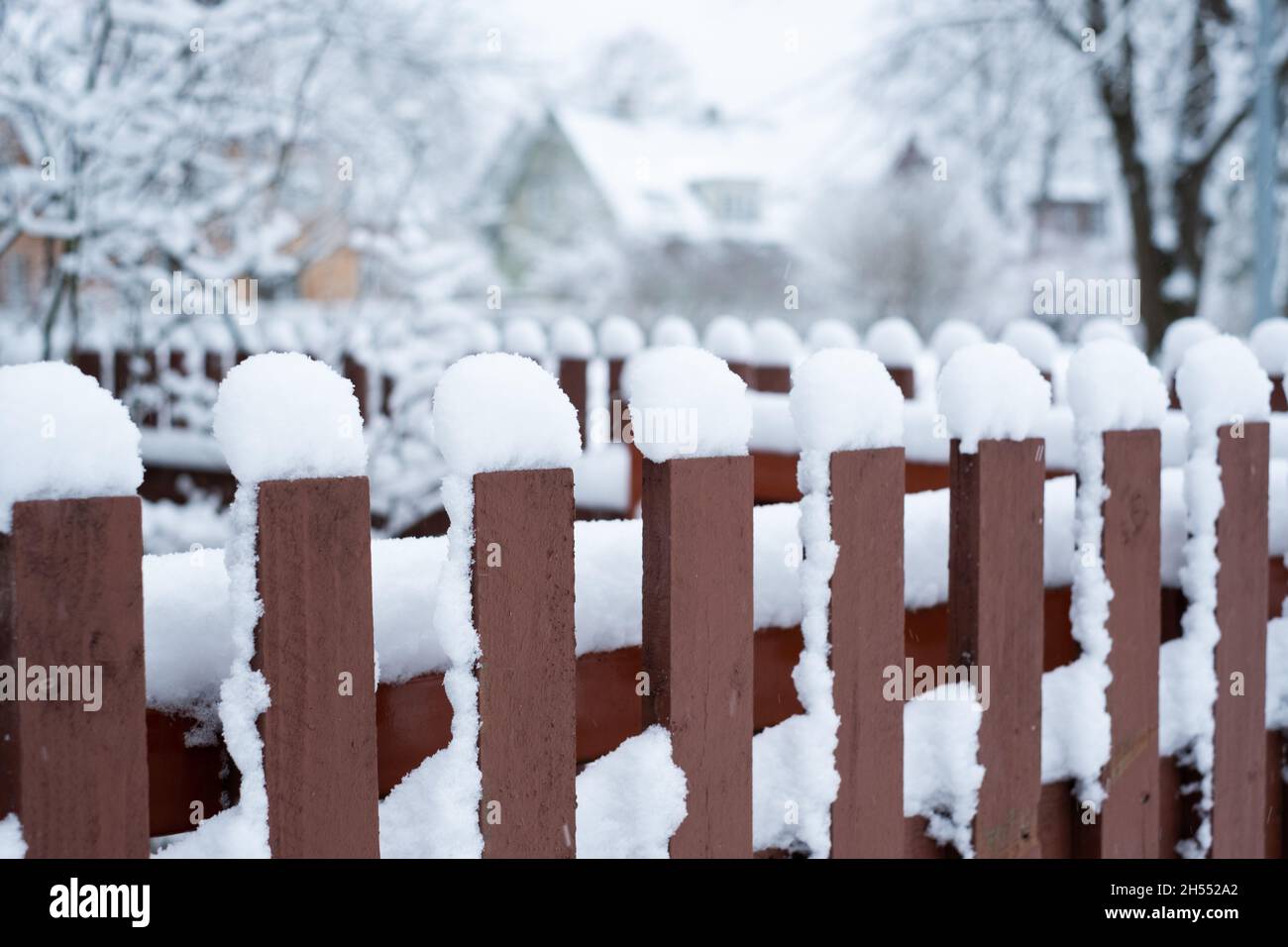 Snow cover. Winter weather. Garden under snow. Close-up of wooden fence covered in snow during winter season. Stock Photo