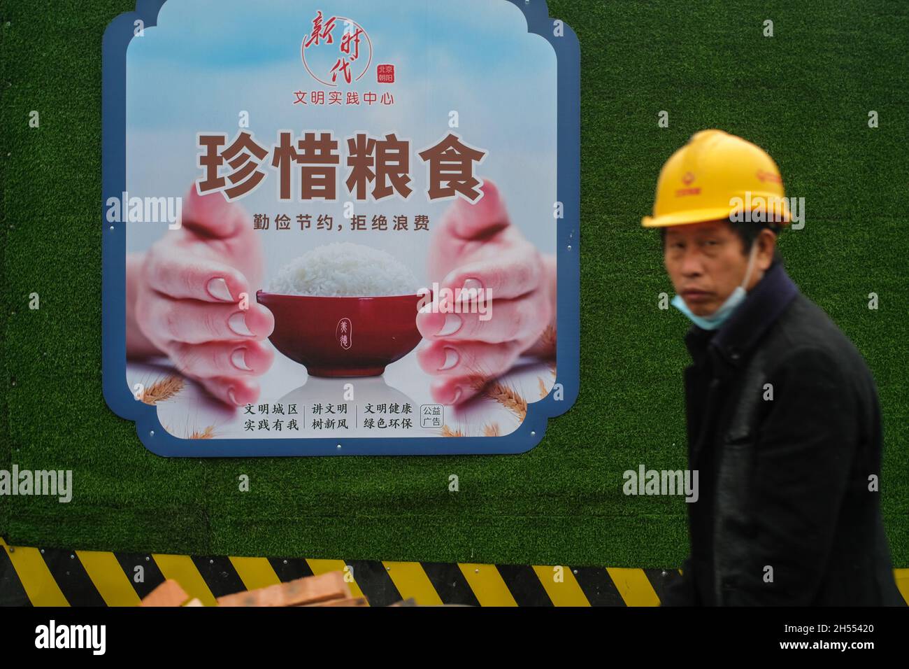 A worker walks past a billboard featuring Cherish your food in Beijing, China. 06-Nov-2021 Stock Photo