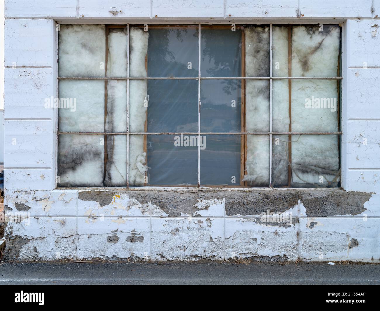 Insulation showing through windows on an old concrete building Stock Photo