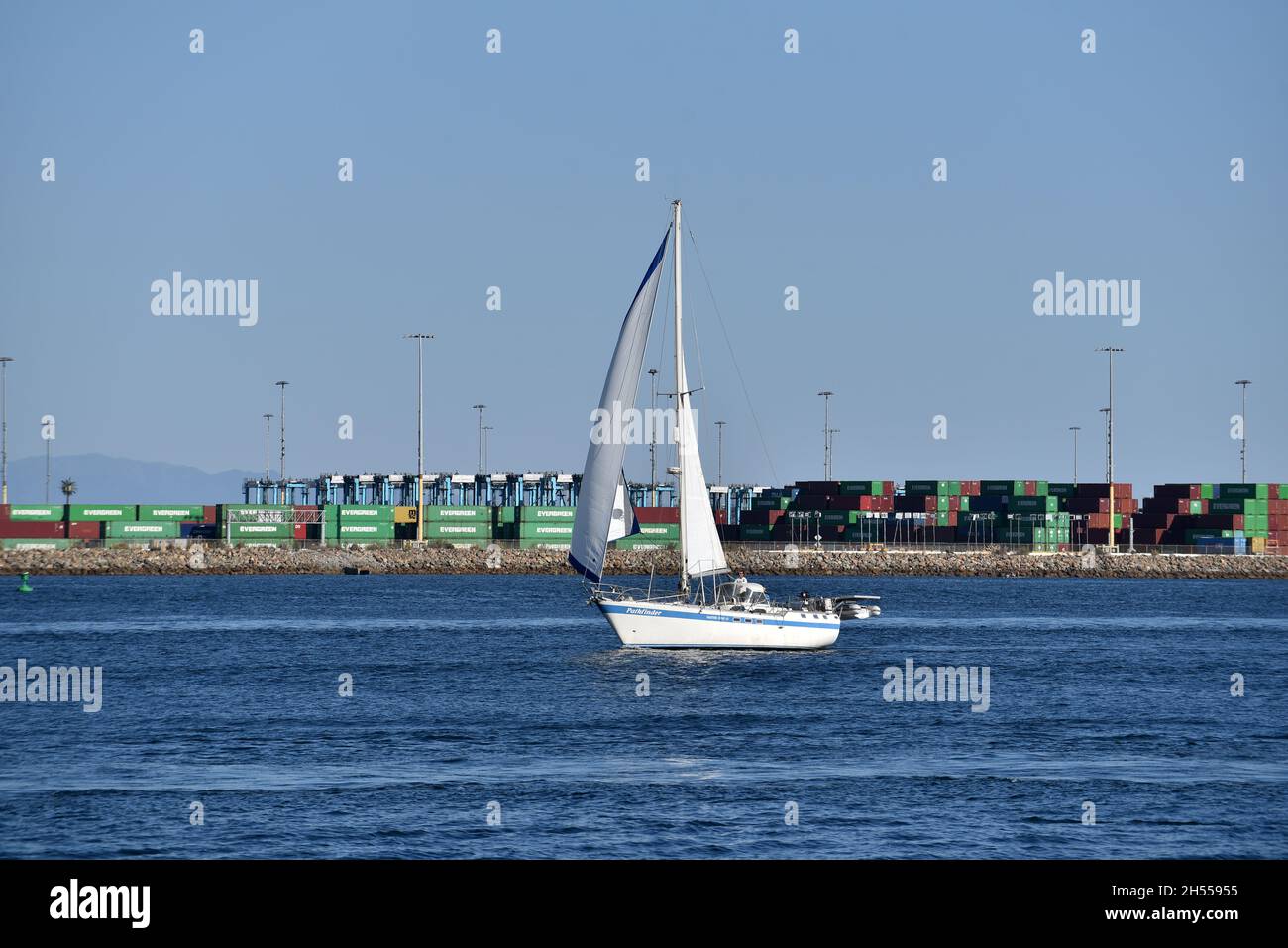 Los Angeles, CA USA - October 15, 2021: Sailboat passing shipping containers and gantry cranes in the main channel of the Port of Los Angeles Stock Photo