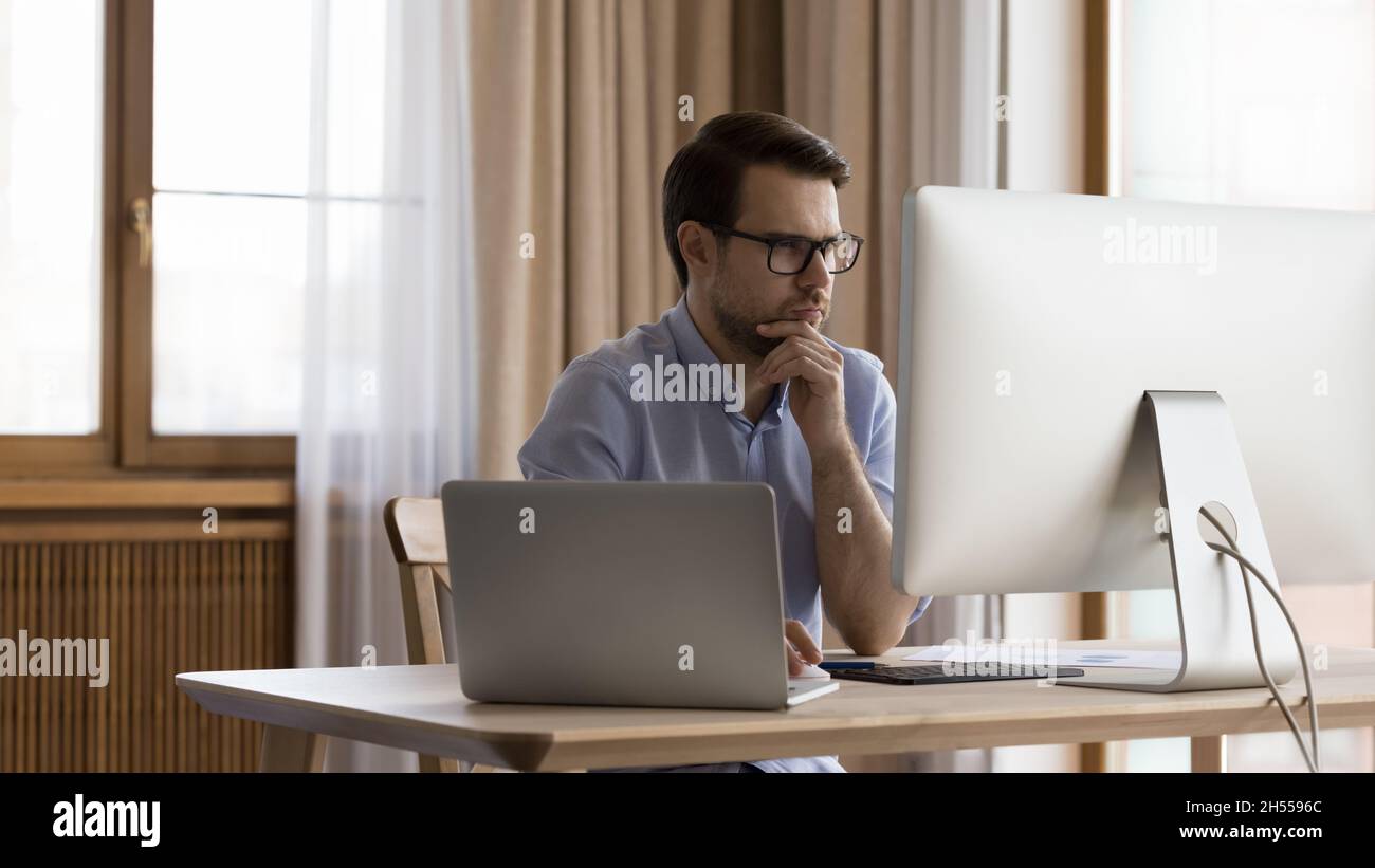 Concentrated young 30s businessman working on computer in office. Stock Photo