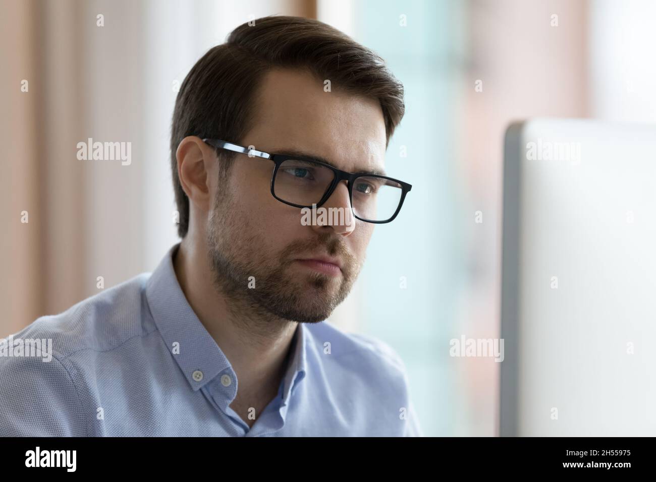 Pensive serious young businessman working on computer. Stock Photo