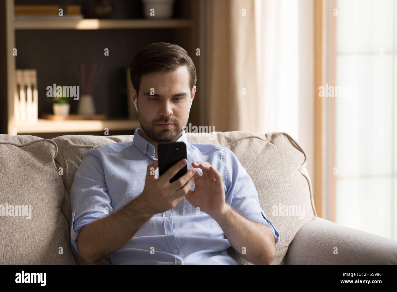 Happy young handsome man in earbuds using cellphone. Stock Photo