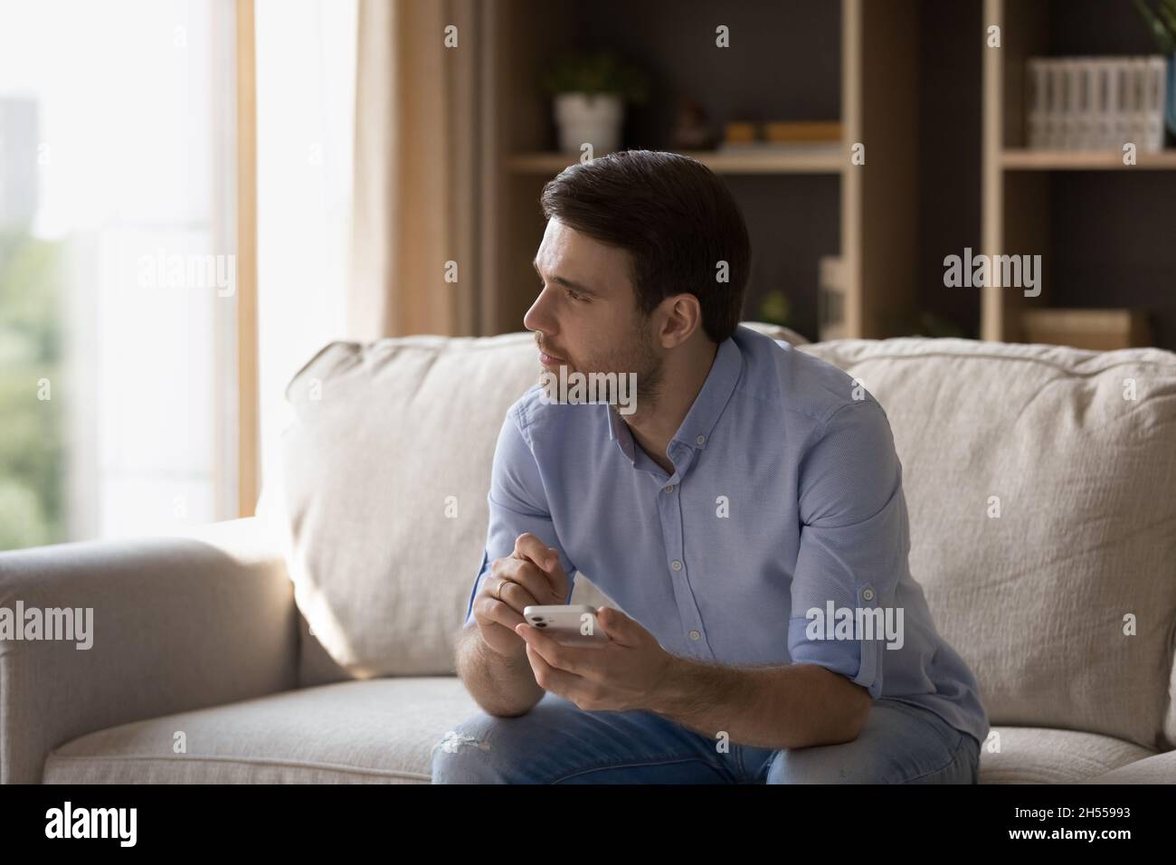 Happy young man using cellphone at home. Stock Photo