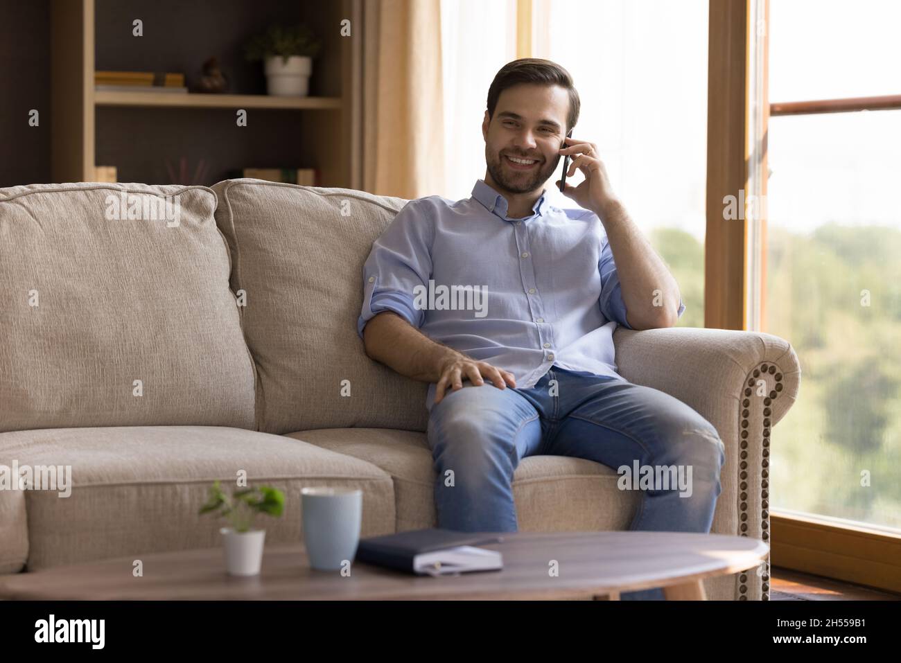 Smiling handsome young man holding cellphone conversation. Stock Photo