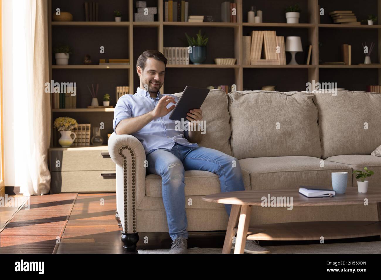 Happy young relaxed man using digital touchpad gadget. Stock Photo
