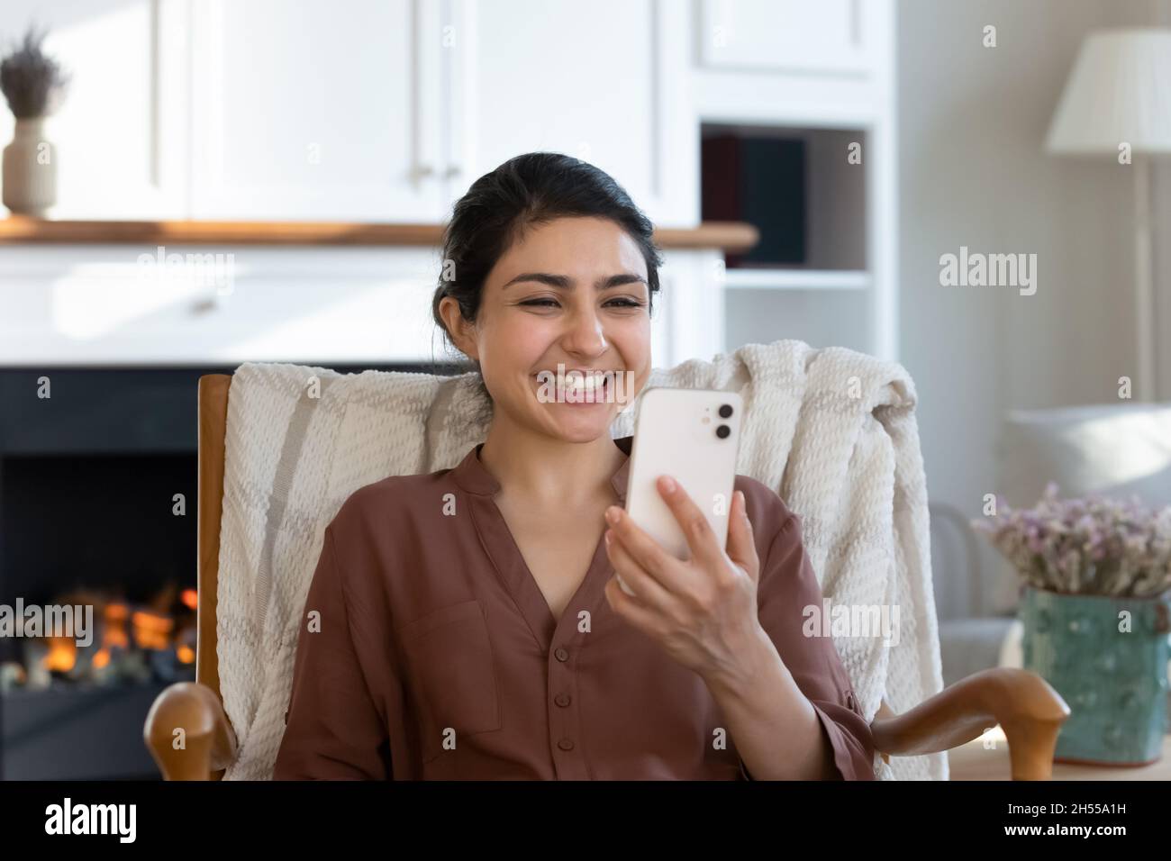 Overjoyed Indian female read sms on smartphone while relax indoor Stock Photo