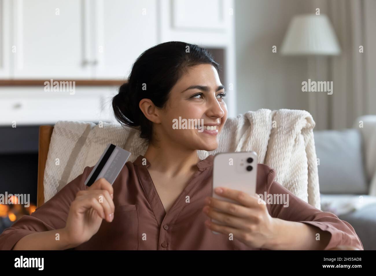 indian woman holds credit card and smartphone buying goods online 2H55AD8