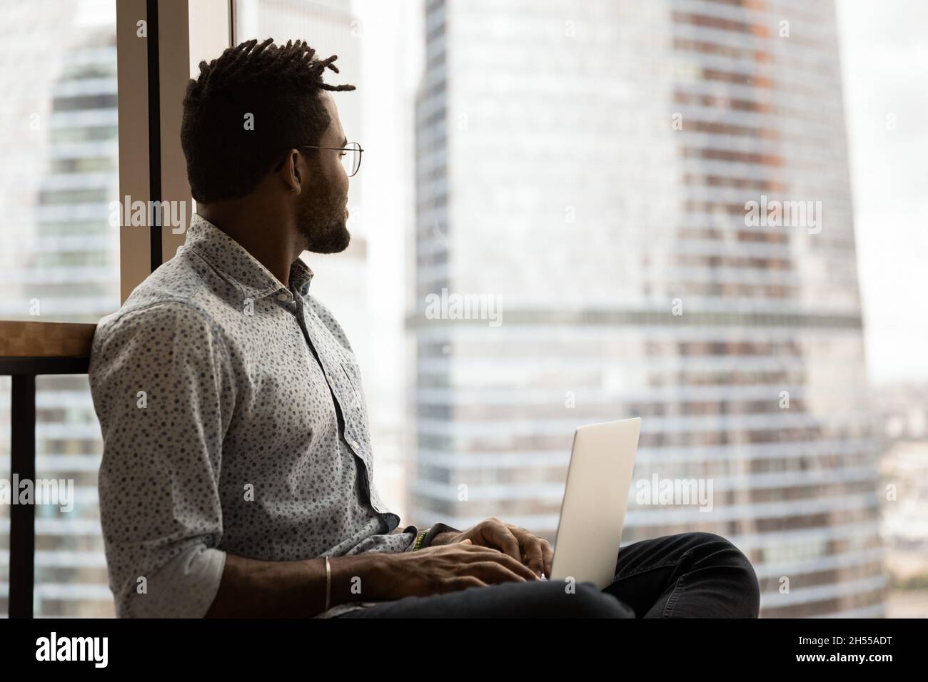 Dreamy smart young african american freelancer working on computer. Stock Photo
