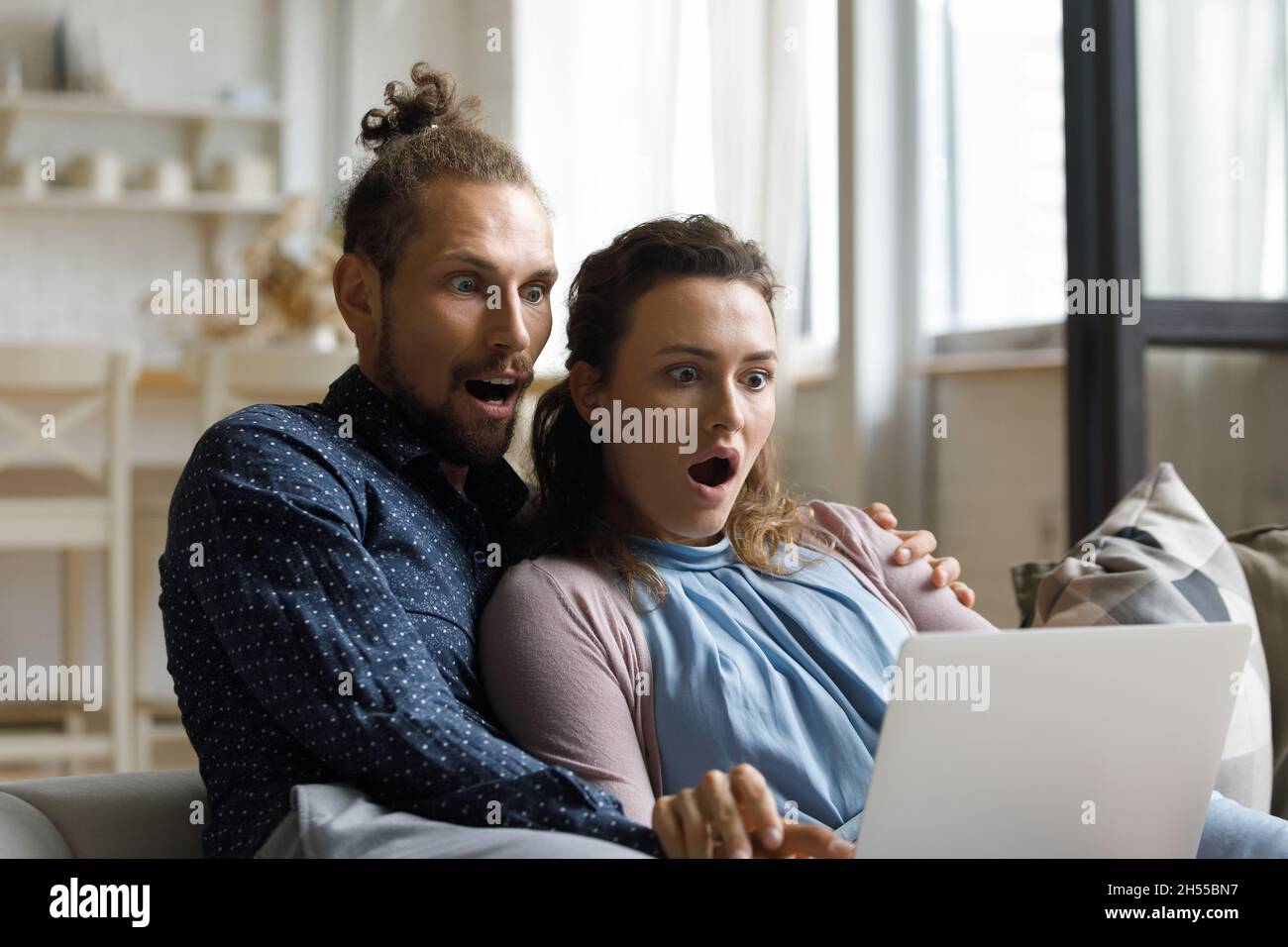 Shocked young couple looking at computer screen. Stock Photo