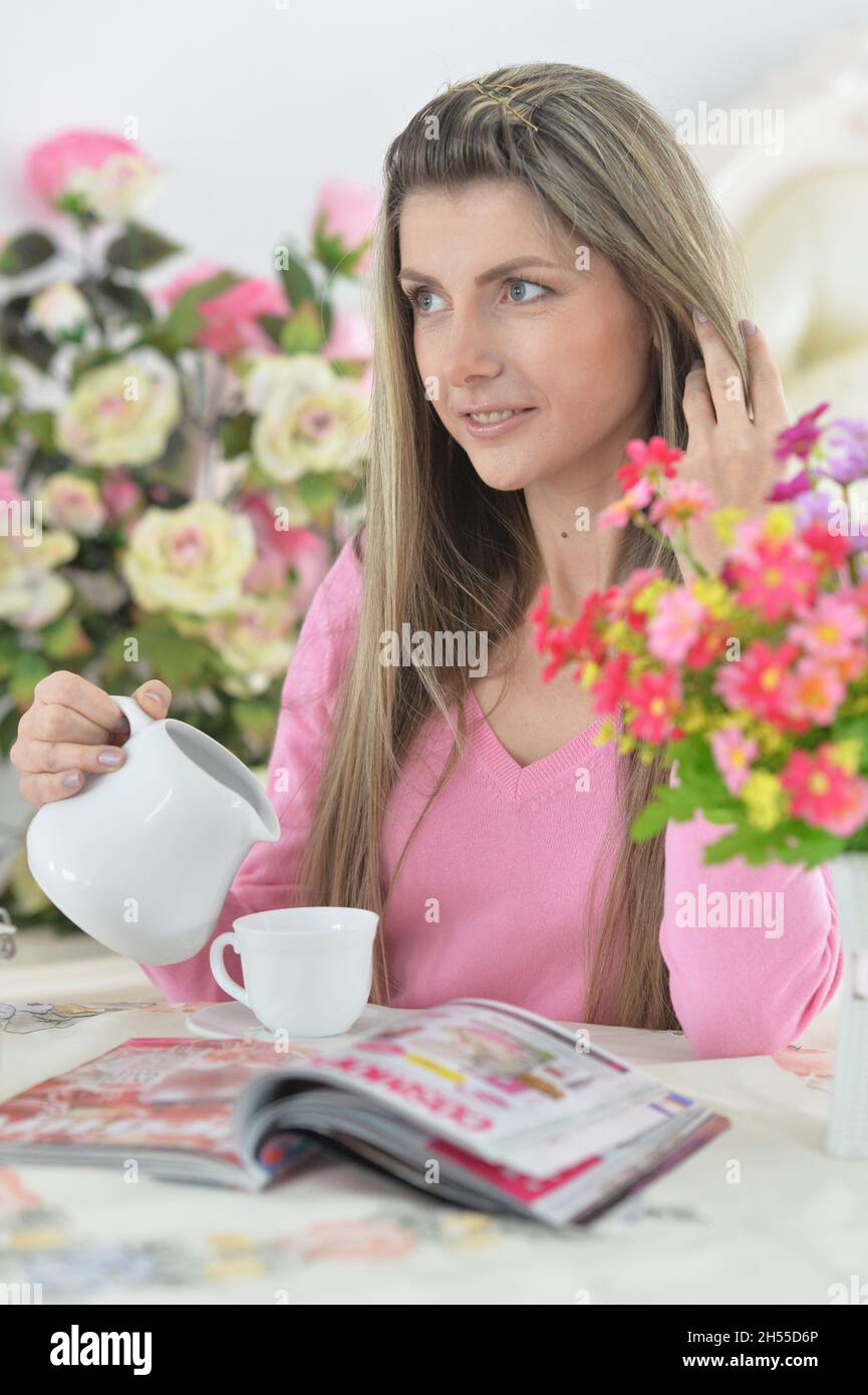 Beautiful young woman with cup of tea reading magazine Stock Photo Alamy