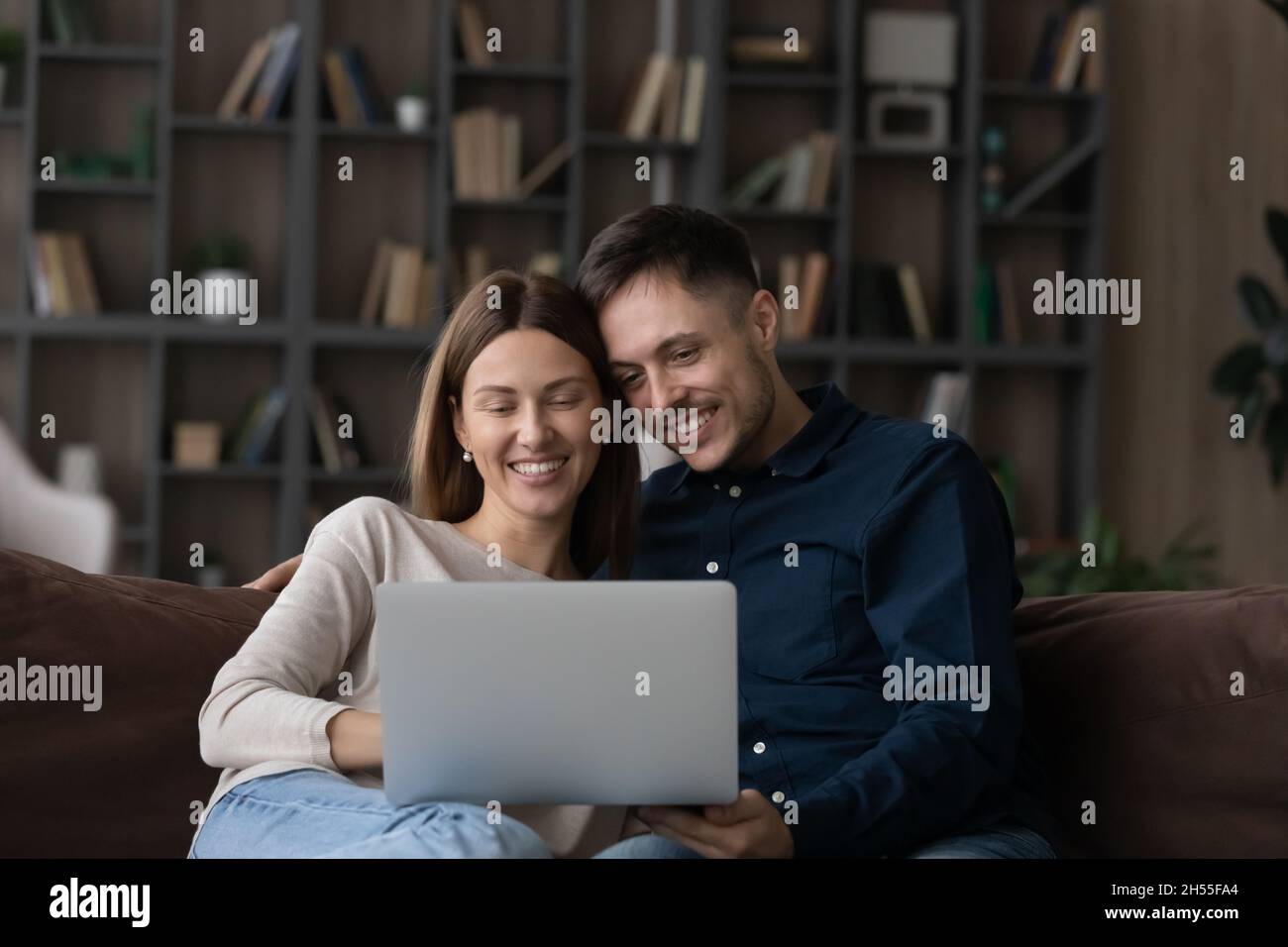 Happy Caucasian couple using laptop, relaxing on couch together Stock ...
